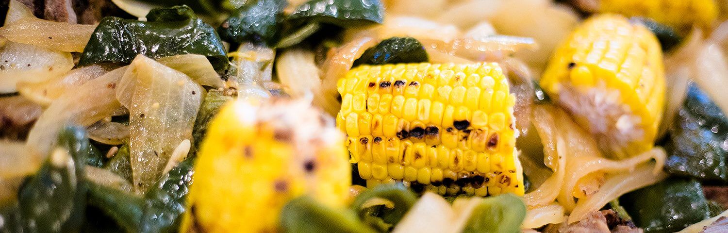Close up of grlled corn, onion, pepper and steak